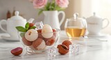 Lychees in Glass Bowl with Ice Cubes and Mint Leaves on Marble Countertop with Tea Set in Background