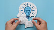 © Ramzan - Hands assembling puzzle of a head with a bright idea lightbulb inside
