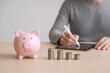 © Generative AI - Saving Money Concept: Pink Piggy Bank, Coins, and Man Planning Finances on Tablet