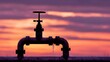 © sungedi - Old rusty pipe valve against a vibrant sunset.