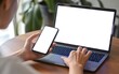© RAFIQ - Close up of a person s hands using a laptop and holding a smartphone both with blank screens suggesting productivity and digital connection in a modern workspace