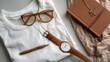 © somsri - Flat lay of a white T-shirt with accessories around it like glasses, watch, and notebook