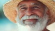 © ziya - Photograph of a smiling elderly man with a white beard wearing a straw hat against a blue background.