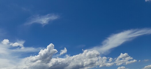 Wall Mural - The clouds that are fluffy and stacked at the bottom are cumulus clouds. Clouds that appear thin and feathery in higher parts of the sky are cirrus clouds.