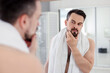 © New Africa - Handsome man before shaving looking at mirror in bathroom