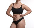 © New Africa - Liposuction. Woman in underwear touching her belly on white background, closeup