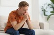 © New Africa - Sad thoughtful man on sofa at home