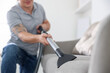 © New Africa - Man cleaning sofa with vacuum cleaner at home, closeup