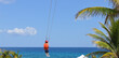 © charlie - Boy on zipline in paradise on vacation with blue sky and palm trees