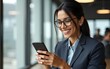 © feng - Smiling Latin Hispanic mature female businesswoman holding smartphone in office trading app, working online. Young Indian business woman manager ceo using cell phone mobile application. Vertical
