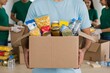 © Poetra RH - A volunteer holds a box full of donated food items, ready for distribution. This image represents charity, community support, food bank, donation, and helping those in need.