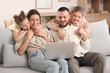 © Pixel-Shot - Happy parents with their daughters watching cartoons on laptop at home