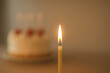 © Photo_K - Flickering Birthday Candle Flame with Blurred Cake – Minimalist Close-Up