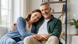 © janitha - Happy Middle-Aged Couple Hugging and Relaxing on Sofa at Home