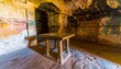 © Isda - Ancient table inside a cave chamber with faded frescoes.