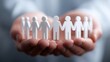 © liliyabatyrova - Hands holding paper figures representing community and support in a collaborative effort for social unity