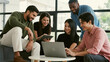 © Purwadani - Group of young business people working together on laptop at modern office.