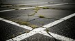 © Oxiya - Cracked asphalt parking lot with weeds growing through the surface and white painted lines