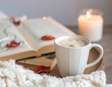 Mug kopi latte putih berbusa dalam suasana musim gugur yang nyaman dengan buku terbuka, daun kering, lilin menyala, dan selimut rajutan. Latar belakang lembut, nada hangat, komposisi damai.