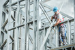 © Tomasz Zajda - Construction Worker Assembling Metal Framework on Building Site During Daylight