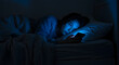 © wibiwisnu - A depressed teenage girl lies in bed in a dark room, illuminated by the bluish glow of her smartphone. Concepts for mental health, social media, cyberbullying, anxiety.
