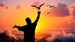 © Pasan - Silhouette of a person with arms raised and birds flying against a vibrant sunset sky over the ocean