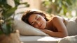 © 沈军 贡 - A young woman sleeps peacefully with soft natural light and green plants around her, indicating relaxation and good sleep quality.