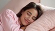 © 沈军 贡 - A young woman sleeps comfortably on a soft pink pillow in a cozy bedroom, appearing relaxed and peaceful.