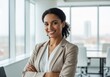 © SHAPLA - Confident businesswoman smiling in modern office with arms crossed