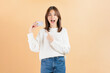© sitthiphong - Cheerful beautiful Asian woman holding credit card isolated on beige color background.