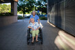 © Halfpoint - Older caregiver pushing senior woman in wheelchair.