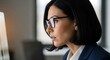 © Fefey - Focused professional businesswoman in glasses working diligently on a computer in a modern office, side view close-up.