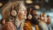 © Oulaphone - The image shows a diverse group of people wearing headphones, enjoying a moment of relaxation and focus in a modern, vibrant environment.