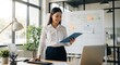 © budi - Empowered woman overseeing project schedule in bright modern office environment