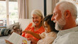 © Monkey Business - Granddaughter Reading With Grandparents On Sofa At Home