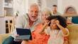 © Monkey Business - Granddaughter And Grandparents On Sofa At Home Streaming Horror Show On Digital Tablet