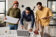© TrueFrame Collective - Medium long shot of three South Asian men working together on business strategy in modern office