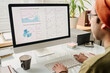 © TrueFrame Collective - Selective focus shot of young specialist sitting at table in modern office working on charts and graphs on desktop computer