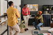 © TrueFrame Collective - Group of three South Asian developers standing and sitting in modern office discussing new project