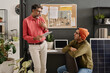 © TrueFrame Collective - Medium long shot of mature Indian man holding digital tablet standing in office talking to his younger colleague