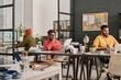 © TrueFrame Collective - Group of three diverse Indian men wearing casual outfits working in modern office, using computers and doing paperwork, copy space