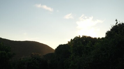Wall Mural - static 4k shot of a sunlit mountain during golden hour. warm evening light glows across the landscap