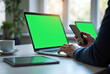 © Ryan Rizky Pratama - Person Using Laptop and Smartphone with Green Screen in Cozy Workspace