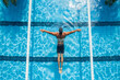 © Creative Hero - Aerial view of a male swimmer performing the butterfly stroke in a clear blue swimming pool with lane lines