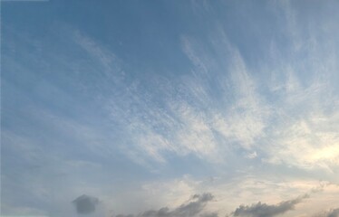 Wall Mural - a vast expanse of a clear blue sky as the background, with several wispy white clouds floating gentl