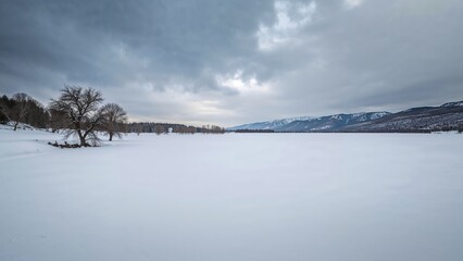 Wall Mural - snowy lake lies quiet beneath a sky filled with clouds