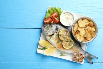 Wall Mural - homemade seafood dish. tasty roasted dorado fish served with vegetables and sauce on light blue wood