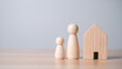 © photostockatinat - A tender scene capturing the essence of family and home, with wooden figurines representing a parent and child alongside a charming house