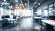 © mila103 - A blurry image of a large office space with many desks and chairs. The room is filled with light and the atmosphere is busy and professional