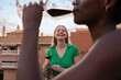 © Milles Team/Stocksy - Happy woman watching her friend drinking red wine